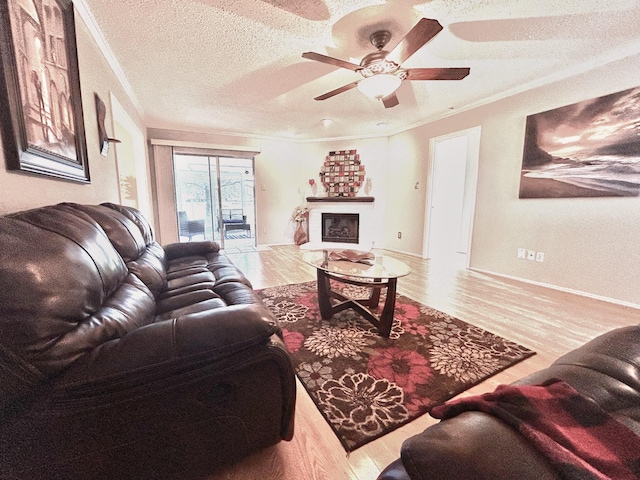 living room featuring a fireplace, a ceiling fan, ornamental molding, a textured ceiling, and wood finished floors