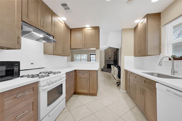 kitchen with light countertops, white appliances, a sink, and under cabinet range hood