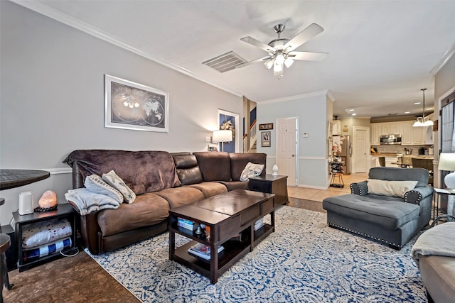 living area featuring ornamental molding, light tile patterned flooring, visible vents, and a ceiling fan