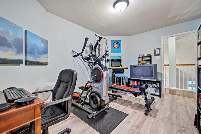 exercise room with a textured ceiling and wood finished floors