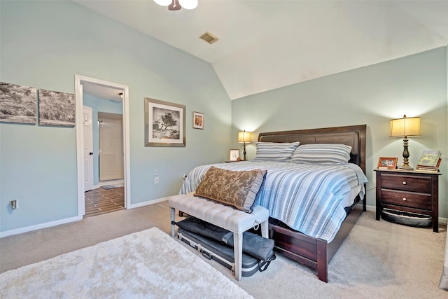 bedroom with lofted ceiling, light carpet, visible vents, baseboards, and ensuite bath