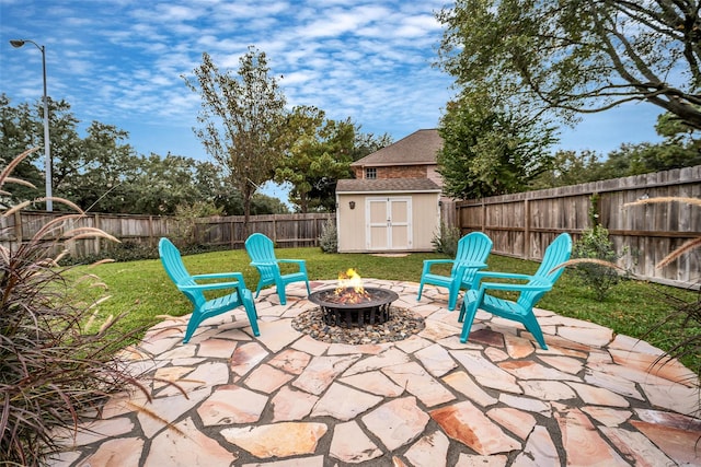 view of patio / terrace with an outdoor fire pit, a storage unit, a fenced backyard, and an outbuilding