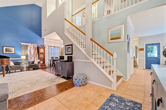 foyer featuring light tile patterned floors, ornamental molding, and stairway