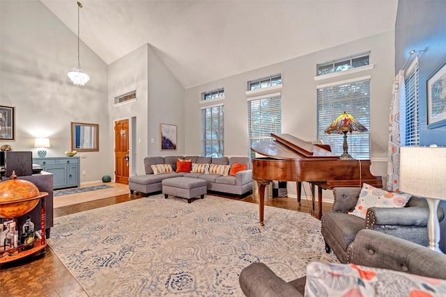 living room featuring high vaulted ceiling, baseboards, and an inviting chandelier