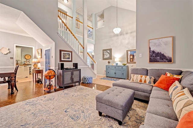 living area with wood finished floors, vaulted ceiling, baseboards, and stairs