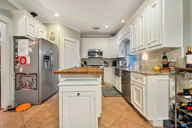 kitchen with a kitchen island, white cabinetry, stainless steel appliances, and light tile patterned flooring