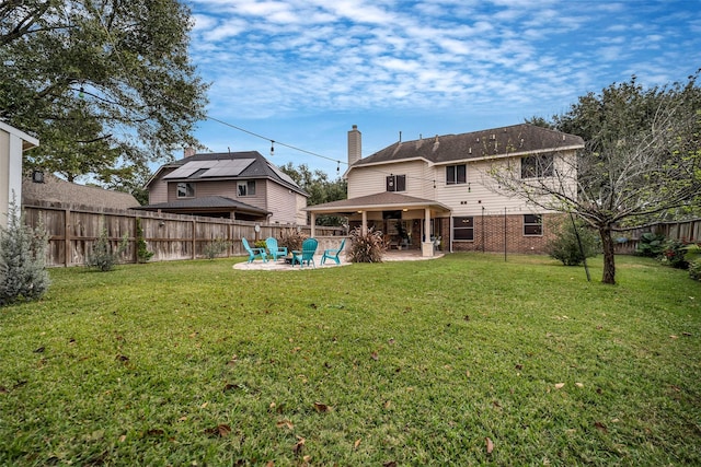 rear view of property featuring a chimney, a patio area, a lawn, and a fenced backyard