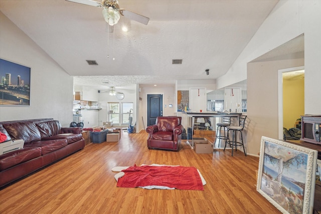 living area with light wood-style floors, visible vents, a textured ceiling, and a ceiling fan