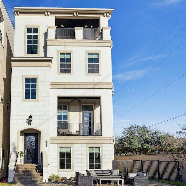 view of front of property featuring a balcony, a patio area, fence, and outdoor lounge area