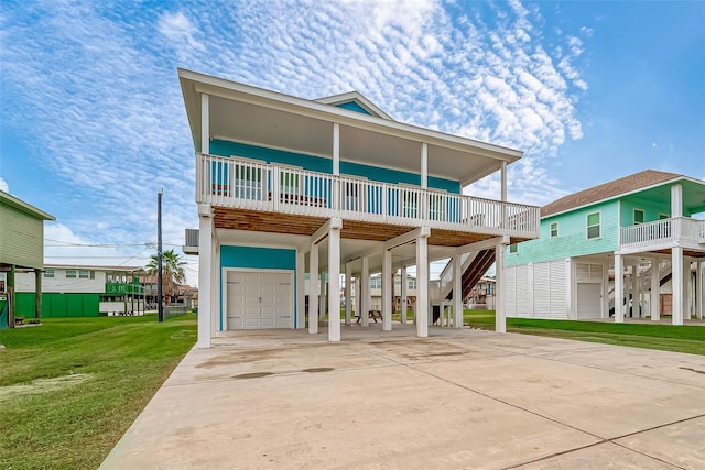 coastal inspired home featuring concrete driveway, a garage, a front yard, a carport, and stairs