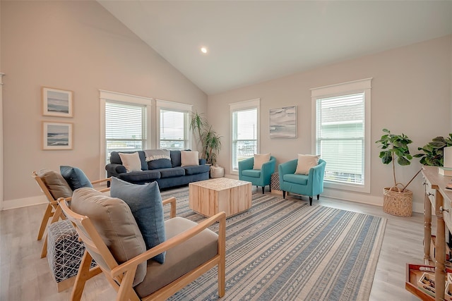 living area with high vaulted ceiling, baseboards, plenty of natural light, and light wood finished floors