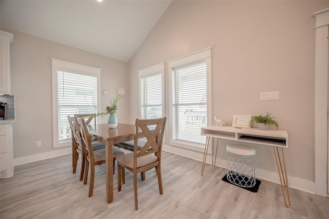 dining area with light wood-type flooring, vaulted ceiling, and baseboards