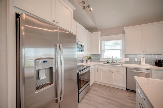 kitchen with stainless steel appliances, tasteful backsplash, a sink, and white cabinetry