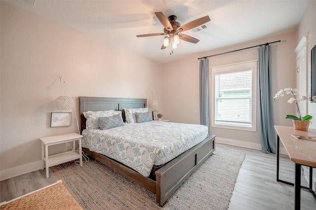 bedroom featuring a ceiling fan, light wood-type flooring, visible vents, and baseboards