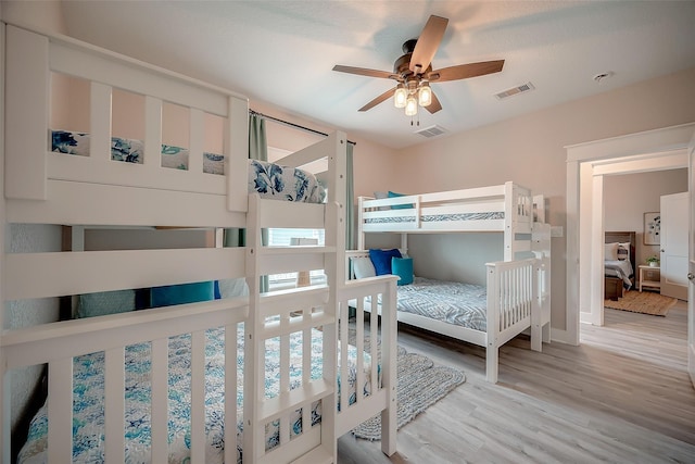 bedroom with a ceiling fan, visible vents, and light wood finished floors