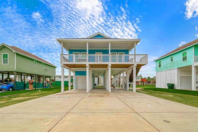 coastal home featuring concrete driveway, stairs, a porch, a carport, and a front yard