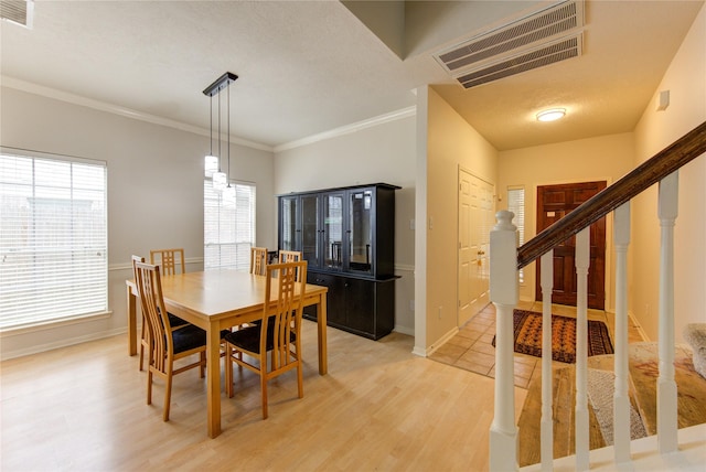 dining area with ornamental molding, visible vents, stairway, and light wood finished floors