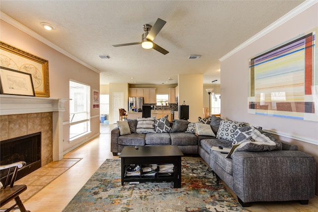 living area featuring ornamental molding, a tile fireplace, and visible vents