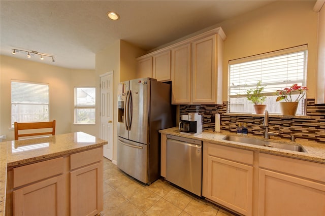 kitchen featuring appliances with stainless steel finishes, a sink, light stone countertops, and decorative backsplash