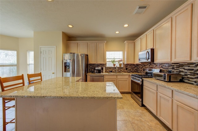 kitchen featuring a center island, light stone counters, stainless steel appliances, and a kitchen breakfast bar