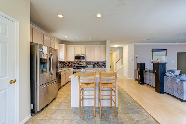 kitchen with a center island, stainless steel appliances, light countertops, open floor plan, and a kitchen breakfast bar