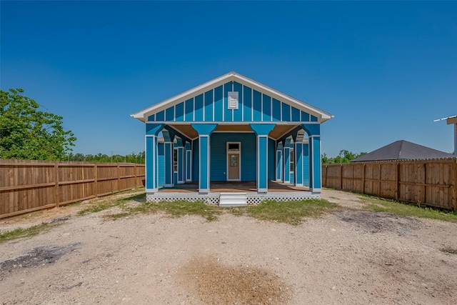 rear view of property featuring a porch, board and batten siding, and fence