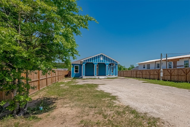 rear view of property featuring an outbuilding, a fenced backyard, and driveway