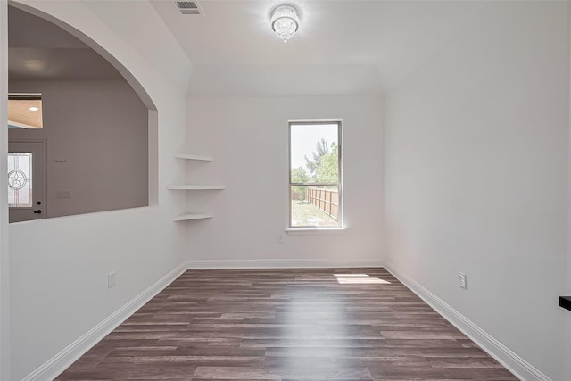 spare room featuring a wealth of natural light, visible vents, baseboards, and wood finished floors