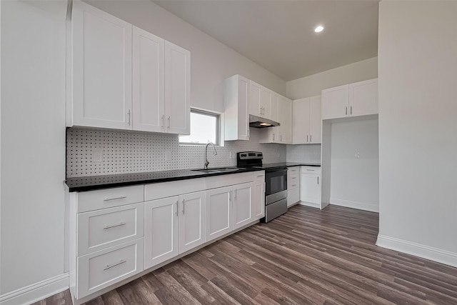 kitchen with tasteful backsplash, dark countertops, white cabinetry, dark wood-type flooring, and electric range