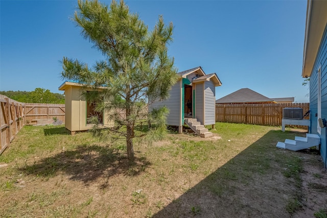 view of yard featuring entry steps, a fenced backyard, and an outdoor structure