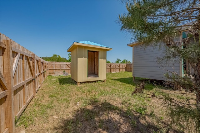 view of yard with a fenced backyard, a storage shed, and an outbuilding