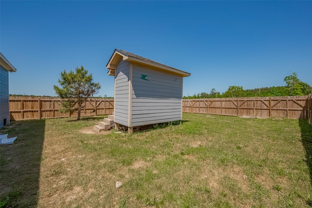 view of yard featuring a storage shed, a fenced backyard, and an outbuilding