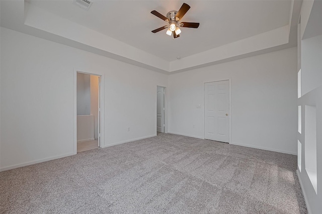 unfurnished bedroom featuring visible vents, baseboards, ceiling fan, a tray ceiling, and carpet flooring