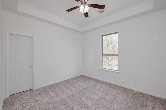empty room with carpet, baseboards, a ceiling fan, and a raised ceiling