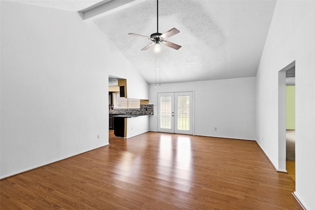 unfurnished living room with french doors, ceiling fan, a textured ceiling, wood finished floors, and beamed ceiling