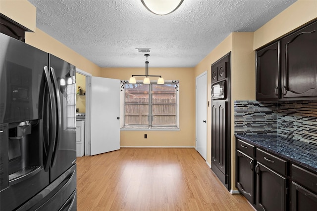 kitchen featuring light wood finished floors, black fridge with ice dispenser, visible vents, and tasteful backsplash