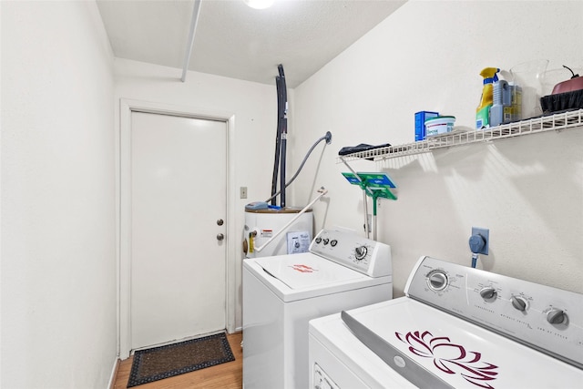 washroom with laundry area, water heater, separate washer and dryer, and light wood-style floors