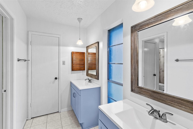 bathroom with a textured ceiling, two vanities, a sink, and tile patterned floors