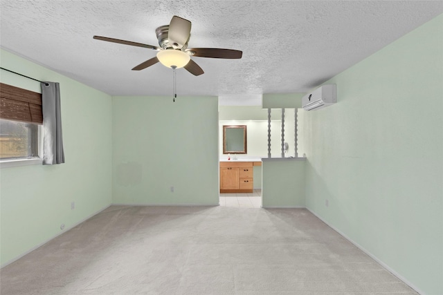 unfurnished room featuring a wall unit AC, a ceiling fan, a textured ceiling, and light colored carpet