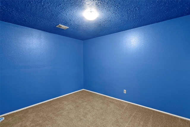 carpeted empty room featuring baseboards, visible vents, and a textured ceiling