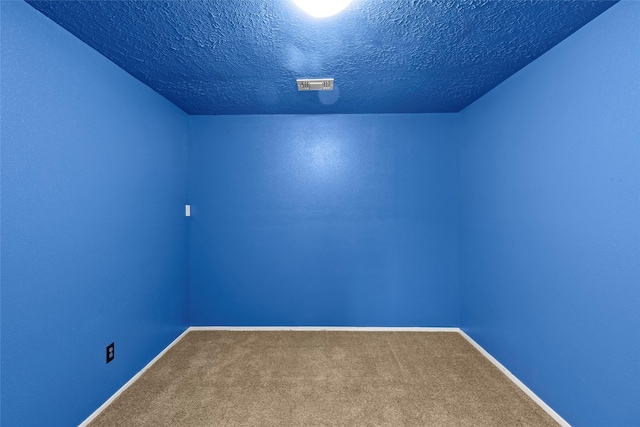 carpeted empty room featuring visible vents, a textured ceiling, and baseboards