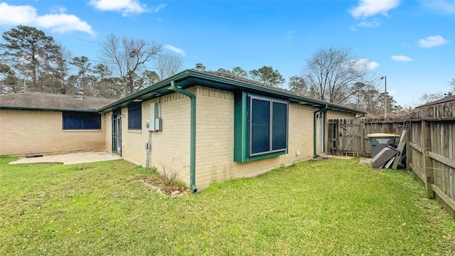 view of side of home with brick siding, a lawn, and fence private yard