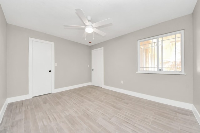 spare room with light wood-style floors, baseboards, and a ceiling fan