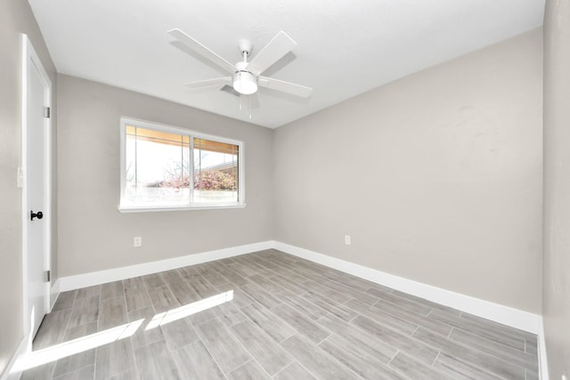 empty room featuring wood tiled floor, baseboards, and ceiling fan