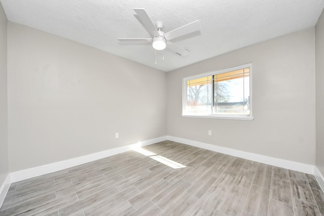 spare room with ceiling fan, a textured ceiling, light wood-style flooring, and baseboards