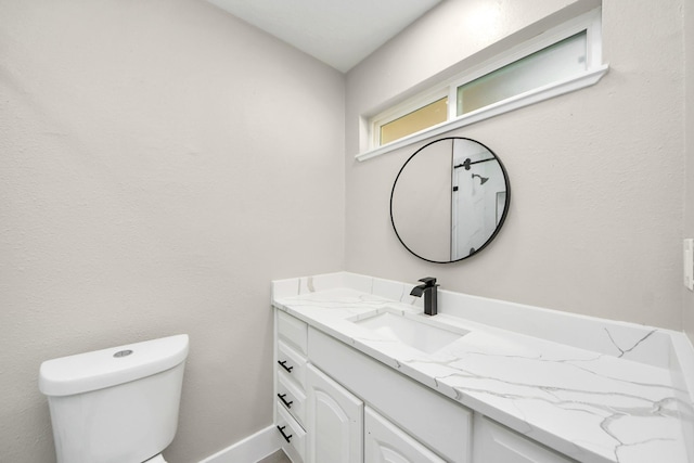 bathroom with baseboards, vanity, and toilet