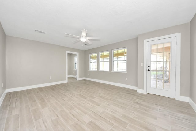 empty room with light wood finished floors, baseboards, visible vents, and a ceiling fan