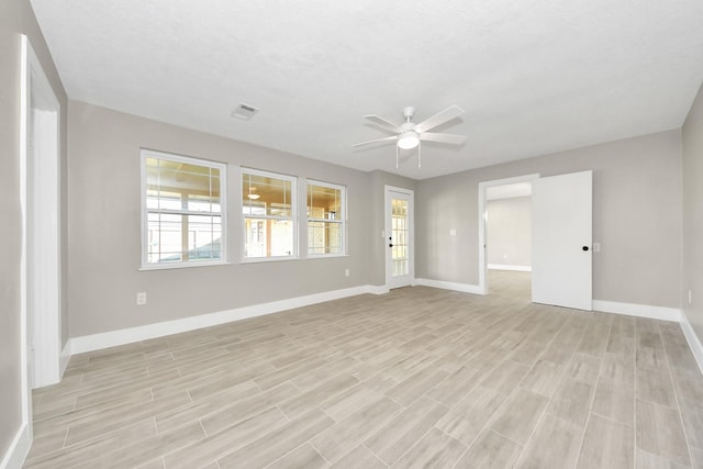 empty room with visible vents, ceiling fan, light wood-style flooring, and baseboards