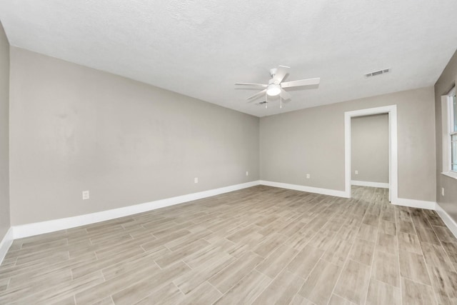 spare room with ceiling fan, light wood finished floors, visible vents, and baseboards