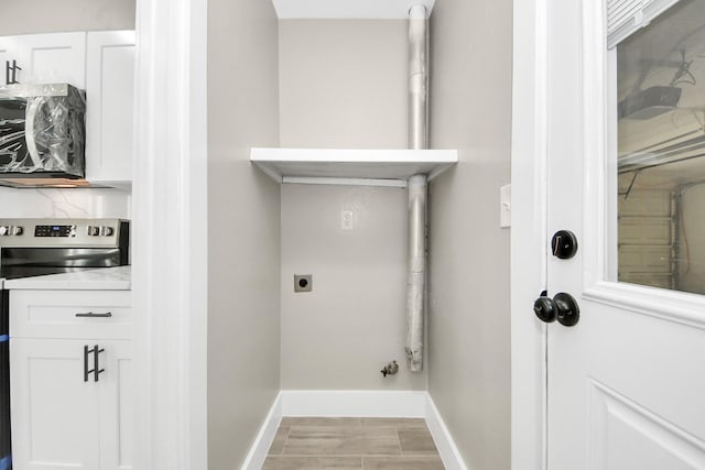 clothes washing area with laundry area, hookup for a gas dryer, electric dryer hookup, and baseboards